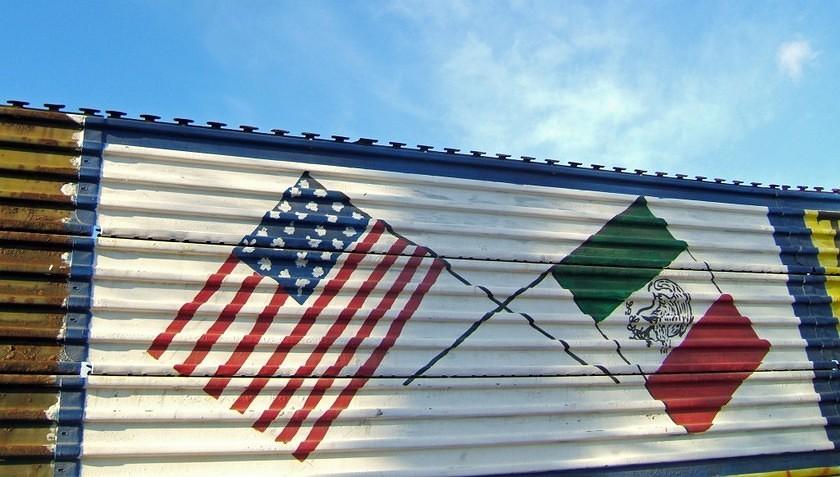 US and MX flags painted on the border fence.