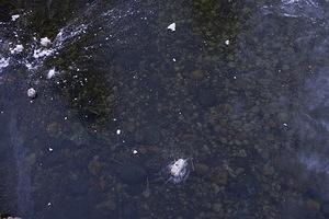 Rocks and snow on the crystal clear ice of the Merced river