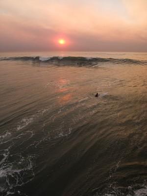 Surfers and a smokey sunset