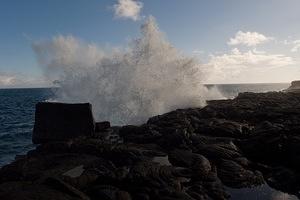 Surf breaks over a lava wall